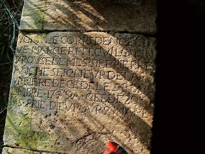 Hangar fermant au nord la cour ouest, pierre tombale de Marguerite Guillotin, décédée en 1745, remployée sur le muret sud.