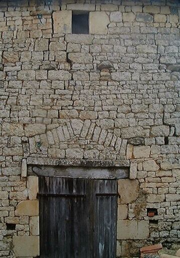 Grange, élévation antérieure ouest, détail de la porte dont le linteau en bois est protégé par un larmier et surmonté d'un arc de décharge.