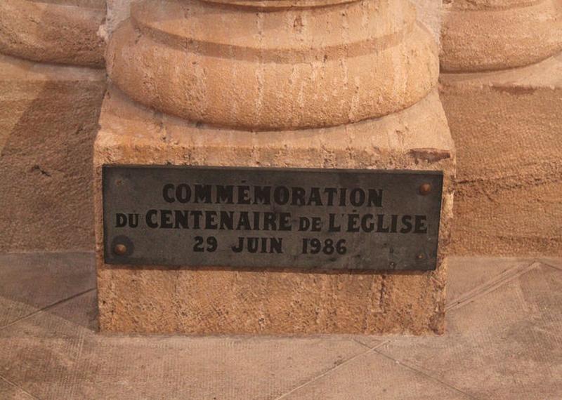 Plaque commémorative du centenaire de la construction de l'église (1986) sur la base du pilier sud-ouest de la croisée.