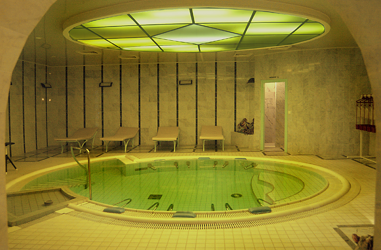 Salle intérieure réaménagée en piscine, à revêtements de marbre vert.