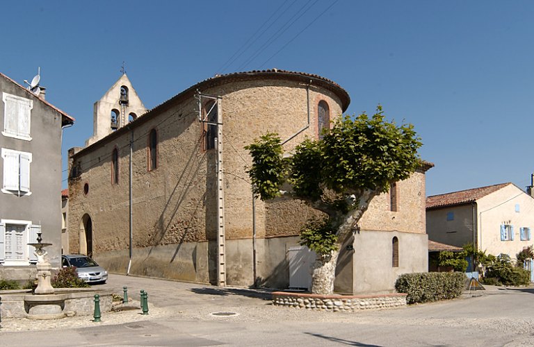 Vue d'ensemble de l'église depuis la place : élévation sud de la nef et chevet avec la sacristie attenante derrière celui-ci.