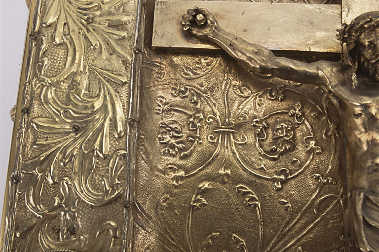 Détail de la partie gauche du plat avec le Christ en croix et le décor Renaissance en relief repoussé à motif végétal.