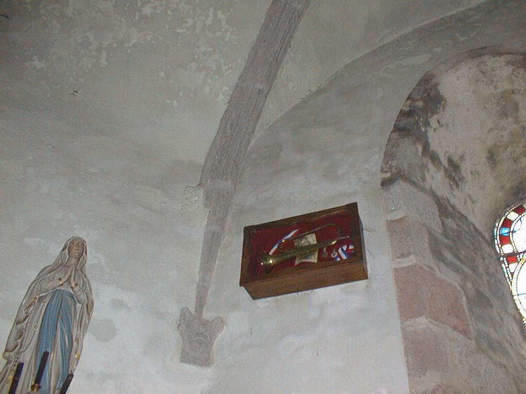 Vue de l'oeuvre commémorative dans l'église paroissiale de Montcalm présentant le fameux clairon et des photographies et médailles de Guillaume Roland.