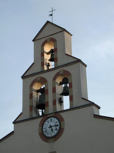 Vue du clocher mur avec ses 3 cloches, surmontant la façade occidentale de l'église.