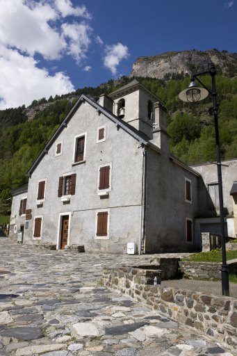 Le clocher de l'église vue depuis la grande rue. Au premier plan, l'ancien presbytère rehaussé.