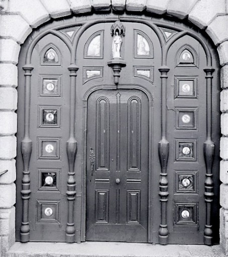 Vue de face de la porte occidentale ornée de 18 plaques de porcelaine enchâssées dans la menuiserie des vantaux.