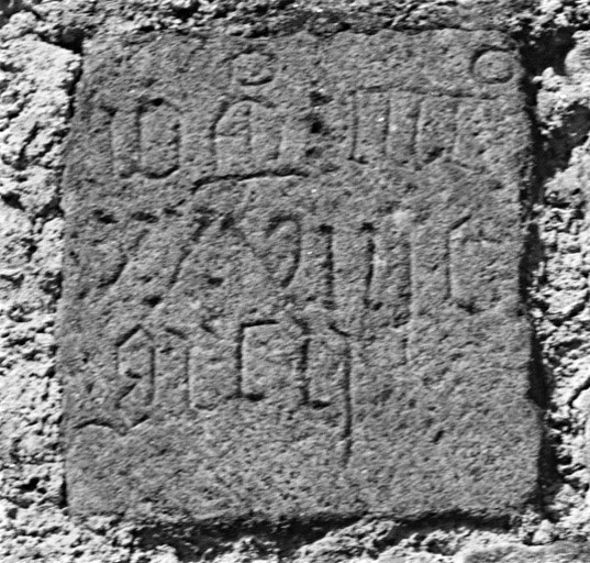 Vestige d'inscription sur une pierre remployée en façade du logis.