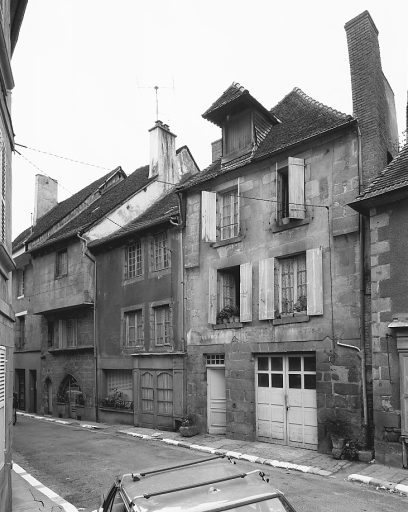 Rue des Tours de l'Horloge, 6 route d'Aubusson ; 2 bis, 2 ter rue des Tours de l'Horloge, 8 route d'Aubusson (2 bis et 2 ter concernent une même maison) ; 2 rue des Tours de l'Horloge. Ensemble de trois maisons (AM 454, 456, 63, 455, 64). (Groupe D1). Maisons de type urbain, à deux étages carrés, bâties sur un parcellaire médiéval étroit ou moyennement étroit ; l'élévation antérieure de la maison située à gauche, avec un deuxième étage en encorbellement traité en pan de bois et torchis, présente deux travées ; celle de la maison médiane présente deux travées légèrement décentrées et une travée latérale aveugle, percée probablement initialement d'une petite baie de la cage d'escalier ; l'élévation de la maison située à droite, de facture plus récente, formant mur de croupe en façade, présente deux travées ; on remarquera les chaînages d'angle, formant légèrement saillie, au niveau du deuxième étage, celui-ci étant peut-être à l'origine traité en pan de bois et torchis.