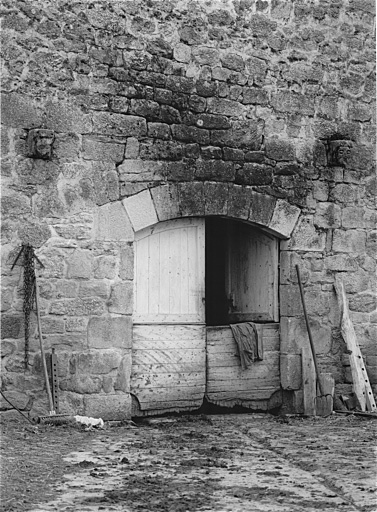 Modillons sculptés d'une tête humaine et d'une tête d'animal, réemployés au pignon d'une grange à Védrennes.