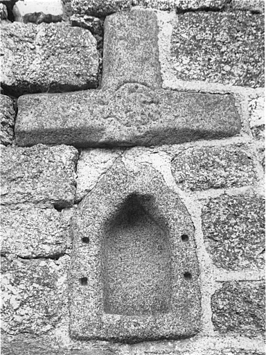 Niche et fragment de croix réemployés dans un mur de grange.