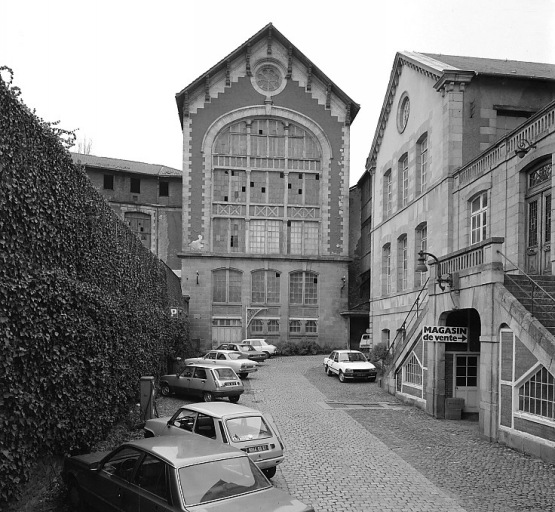 A droite l'entrée des bureaux de l'usine Heyraud (anciens ateliers de décoration de 1853). Au fond, magasin industriel de l'usine de chaussures (ancienne salle des machines de l'usine de porcelaine et entrepôt de stockage de la pâte à porcelaine).