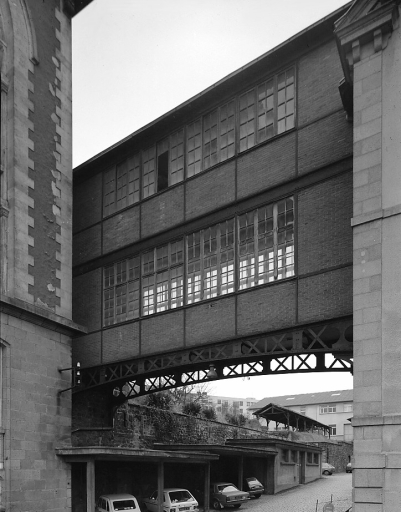 Passerelle reliant les bureaux et magasins de l'usine de chaussures et la partie ouest de l'usine, entre le bâtiment sud et les bâtiments est. Cette passerelle reliait en 1893 les ateliers de tournage et moulage (anciens ateliers de décoration de 1853) à l'atelier de fabrication des assiettes. A gauche, le pignon de la salle des machines.