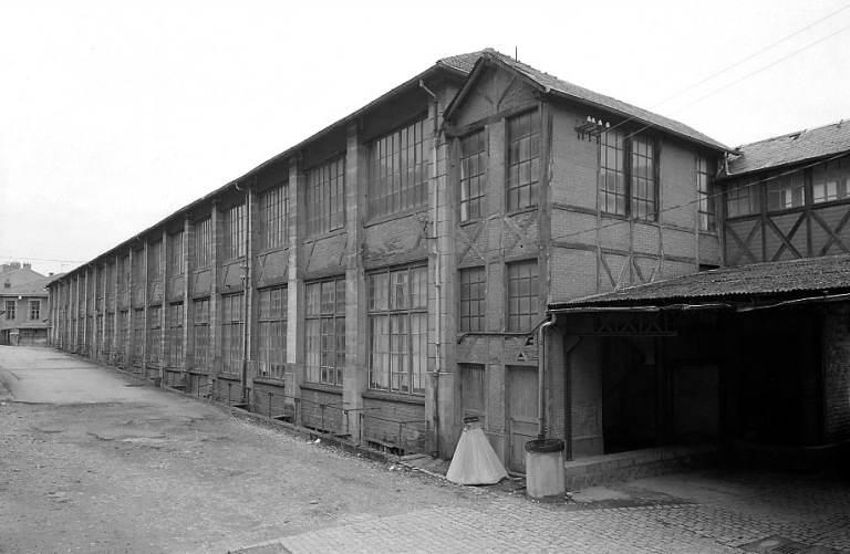 Façade ouest des ateliers de collage et tressage de l'usine de chaussures (en 1893 le rez-de-chaussée serait affecté au stockage du bois). Extrémité sud de la façade : cage d'escalier desservant l'étage.