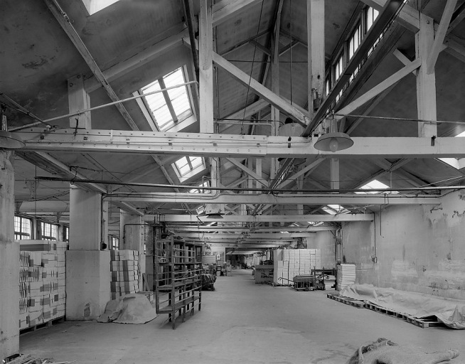 Vue intérieure d'un atelier (anciens ateliers de préparation et de coupe ?). Cet atelier, sans doute édifié entre deux ateliers préexistants, présente divers types d'éclairage zénithaux.