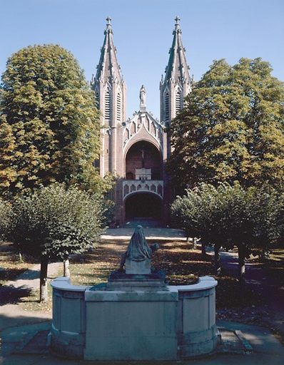 Elévation ouest donnant sur l'esplanade du parc, plantée d'arbres et vue, en premier plan, du monument aux morts.