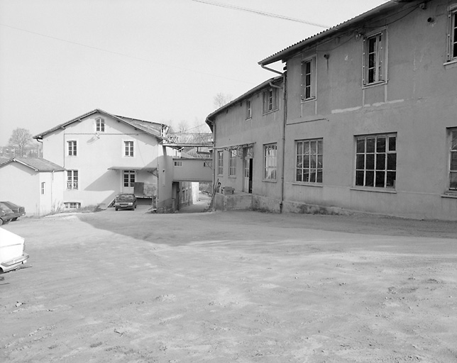 Vue d'ensemble, depuis le sud, ou depuis le portail d'entrée, du moulin de Fer. Au premier plan, à droite : bâtiment B abritant les bureaux et les ateliers de conditionnement de stockage pour envoi.