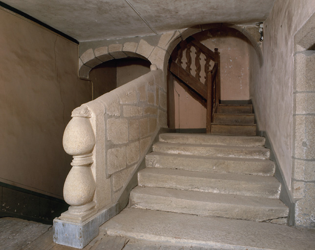 Vue d'ensemble de la dernière volée de l'escalier en pierre et départ de l'escalier en bois avec balustres donnant accès aux derniers niveaux de la tour du château.