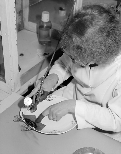 Employée posant le cache en étain et vaporisant 'le blanc relief'.