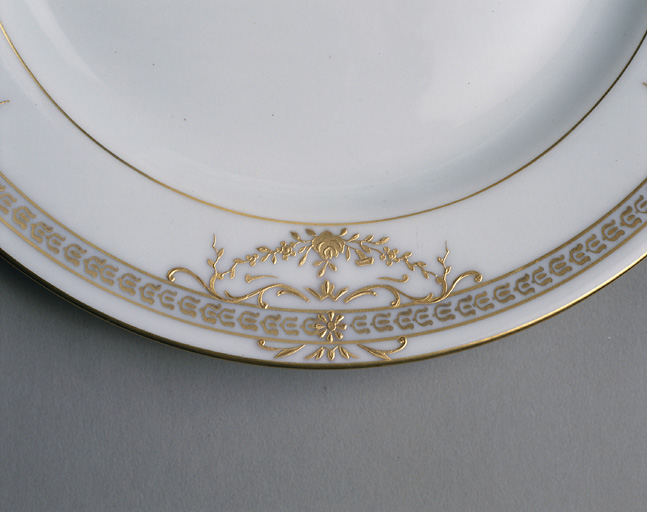 Assiette. Détail du décor après la cuisson du blanc-relief et la projection de l'or avec les caches en étain.