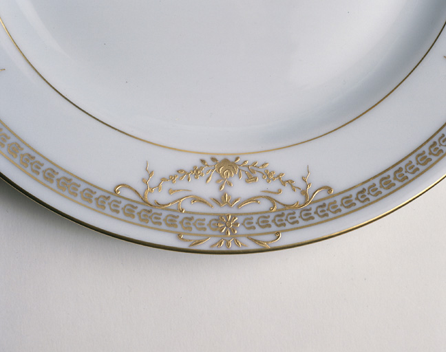 Assiette. Détail du décor après la cuisson du blanc-relief et la projection de l'or avec les caches en étain.