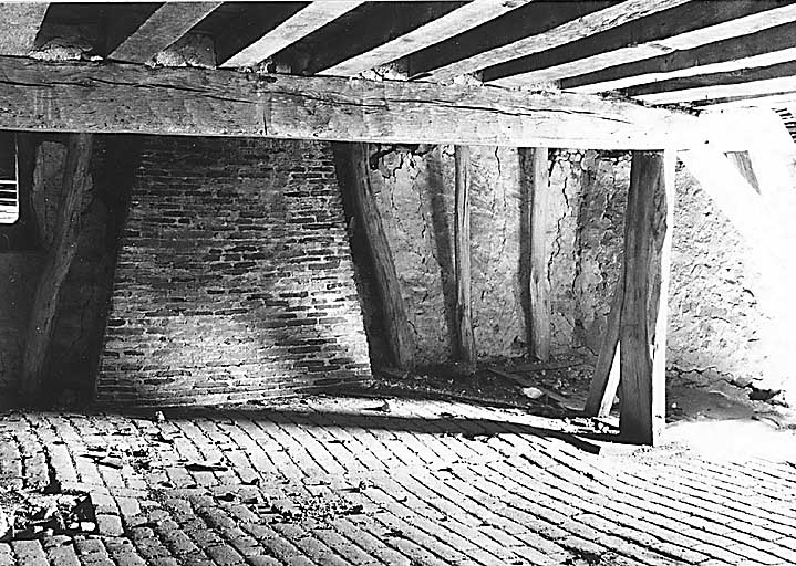 Logis. Etage de comble (1er niveau : comble habitable) ; vue partielle de la partie sud-est : sol pavé de carreaux en terre cuite et conduit de cheminée contre mur sud ; plafond à sommier et solives, soutenu par jambe de force et étai d'appoint.