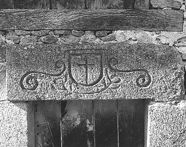 Le Purfier. Ferme (cadastre 1986 D2 722). Porte surmontée d'un linteau (pierre réemployée), orné d'un décor gravé représentant un écu avec croix, accosté de volutes et souligné d'une guirlande végétale stylisée. Vue de détail du linteau.