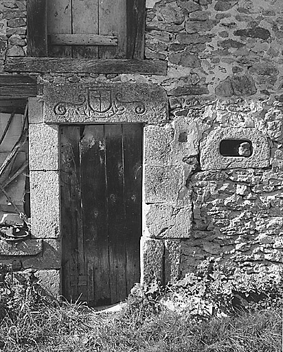 Le Purfier. Ferme (cadastre 1986 D2 722). Vue d'une porte surmontée d'un linteau (pierre réemployée), orné d'un décor gravé représentant un écu avec croix, accosté de volutes et souligné d'une guirlande végétale stylisée.
