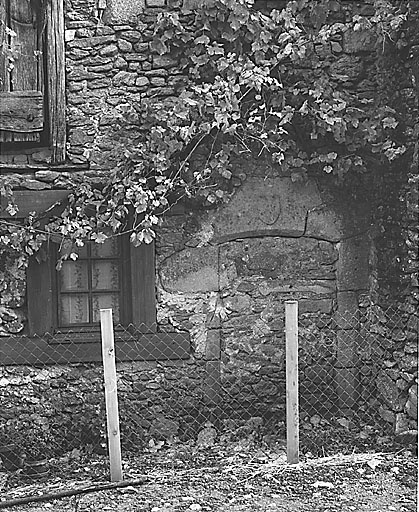 Bussière-Madeleine. Ferme (cadastre 1996 AK 300). Vue partielle de l'élévation antérieure du logis montrant une porte murée dont le linteau en segment d'arc est orné d'un écu.