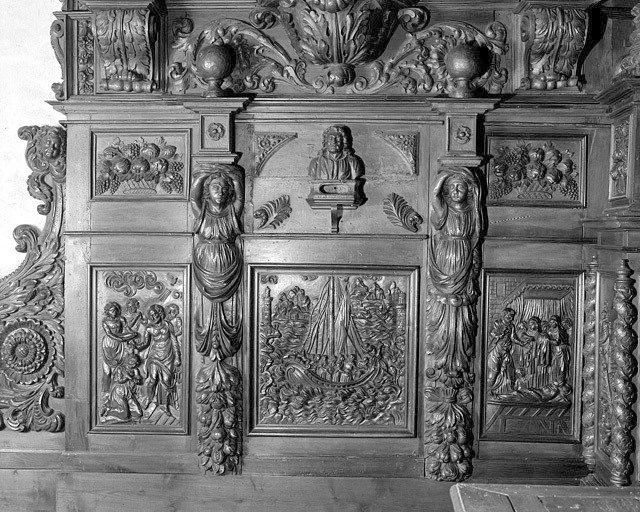 Détail du soubassement de l'aile nord du retable : cariatide de soubassement, terme, chute de feuillages et fruits, encadrant 3 bas-reliefs du cycle de saint Pierre : de gauche à droite, le baptême du centurion Corneille, la tempête apaisée et la résurrection de la veuve Tabitha.