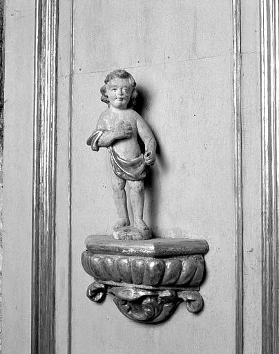 Détail : lambris du pilier nord de l'arc triomphal, statuette de putto sur une console.