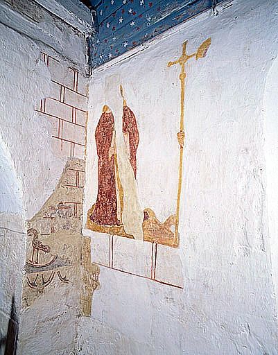 Choeur, angle des murs ouest et nord. Mur nord : apôtre en pied et croix sur hampe (saint Philippe ?). Mur ouest : vestige de décor de faux appareil avec oiseau inscrit dans un cercle.