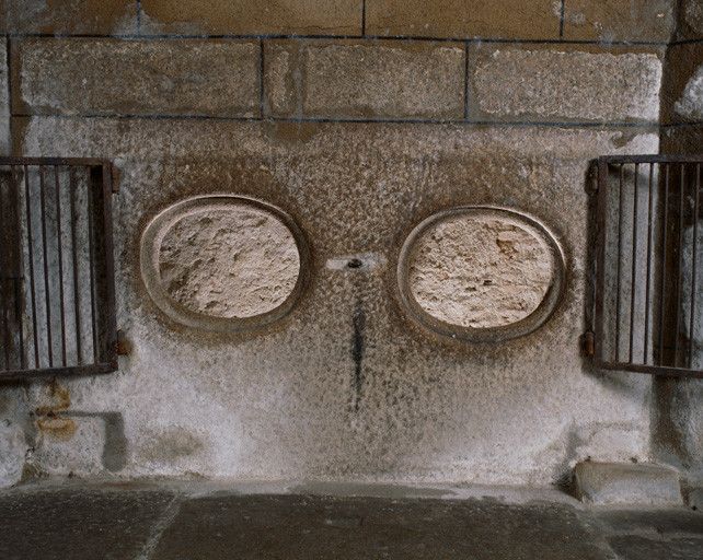 Détail du revers du retable : au centre, à la partie basse, la dalle percée de deux oculi, grilles ouvertes.