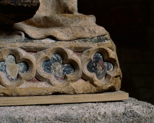 Détail des quadrilobes sculptés et peints sur la plinthe : têtes de personnages.