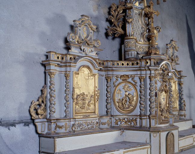 Côté gauche du tabernacle à ailes : bas-relief du Lavement des pieds sur l'aile, et bas-relief du baptême du Christ dans un médaillon sur le pan coupé de l'armoire.