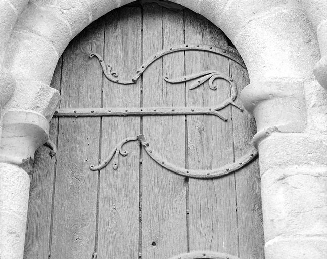 Vue générale de la penture en haut du vantail droit : volutes à l'extrémité des branches du C de la charnière.