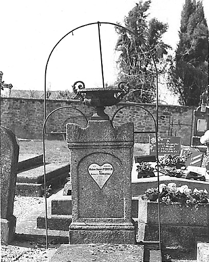 Tombe, section C. Vue de la stèle surmontée d'une urne en fonte, ornée d'une plaque de porcelaine en forme de coeur, datant du début du 20e siècle et accostée et surmontée d'arceaux métalliques servant à la fixation des couronnes mortuaires.