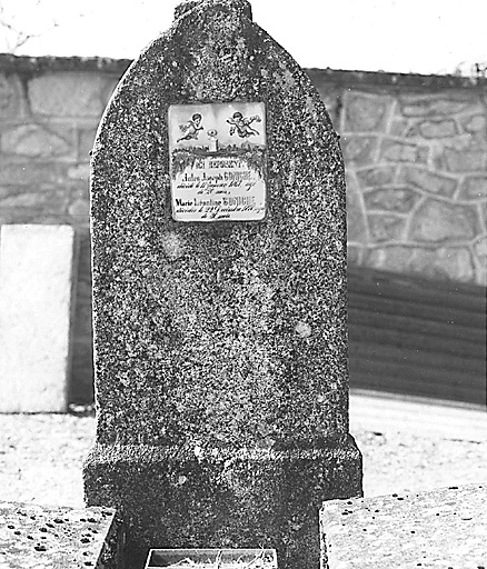 Tombe, section E. Vue de la stèle de la tombe ornée d'une plaque funéraire en porcelaine représentant un paysage champêtre avec une tombe et deux anges la survolant ; plaque funéraire exécutée vers 1870.