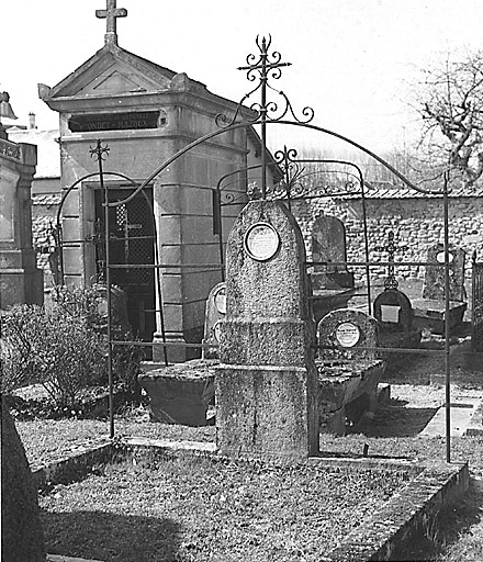 Section A, vue partielle. Vue de trois tombes avec stèle, l'une, au premier plan et de deux autres, jumelées, à l'arrière, comportant une structure décorative verticale en fer, fixée à la stèle et servant à accrocher les couronnes mortuaires.