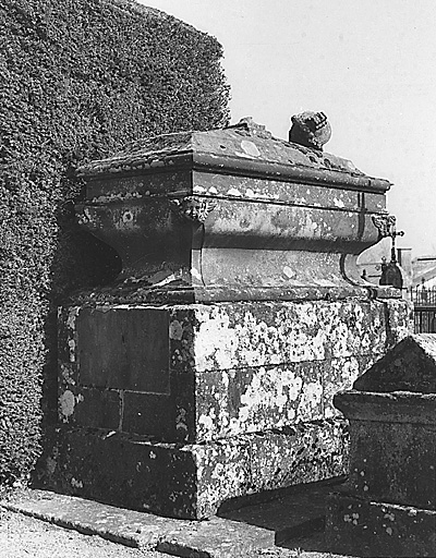 Section B. Vue d'une tombe en forme de sarcophage reposant sur une grande base quadrangulaire ; tombe de style classique, exécutée au cours du 19e siècle et portant un décor sculpté en bas-relief et ronde-bosse (têtes de chérubins ornant les angles et urne surmontant couvercle).