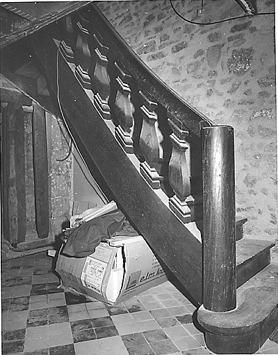 Vue partielle, depuis le rez-de-chaussée, de l'escalier avec rampe en bois ornée de balustres.
