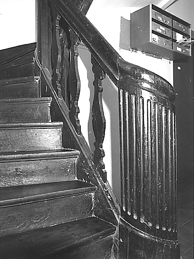 La Souterraine, ville. 3 rue Serpente. Maison construite au cours du premier quart du 20e siècle intérieur. Vue partielle, depuis le rez-de-chaussée, de la première volée de l'escalier tournant et du départ de la rampe en bois, ornée de balustres plats.