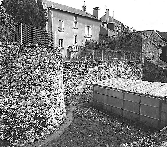 Vue, au premier plan, de la base de la tour dite de la Vigne et en arrière-plan, des vestiges du mur d'enceinte sud.