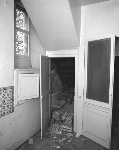 Premier étage, couloir aménagé en fond de bâti. Vue d'une des fenêtres ouvrant sur la cour (fenêtres datant du 16e siècle, entourées extérieurement d'un décor de rocaille), de la volée de l'escalier en bois montant au deuxième étage (escalier aménagé au cours du 19e siècle).