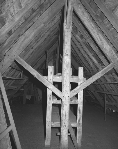 Vue du deuxième niveau de l'étage de comble accessible par un escalier droit en charpente. Vue de la partie haute d'un des cinq poinçons de la charpente et d'étagères latérales aménagées sous les deux versants du toit et ayant probablement servi à ranger des objets liés à l'artisanat de la tapisserie.