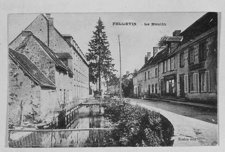 Carte postale ancienne montrant 'Le Moulin' du Pont-Roby, vers 1910. Vue en enfilade depuis le bas de la rue du Pont-Roby, les bâtiments du moulin implanté en aval du pont sont visibles sur la gauche.