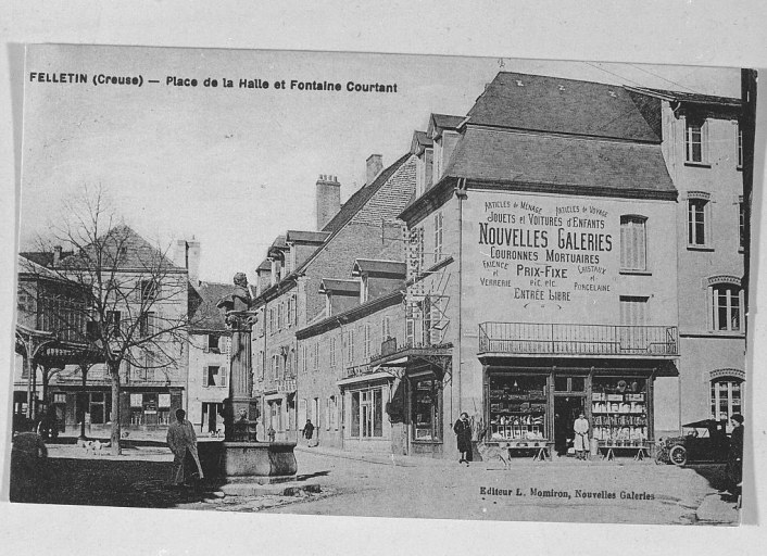 Vue partielle de la place. Cette vue, prise depuis la Grande Rue, montre le carrefour de la place et de la route d'Aubusson. Sur cette vue sont visibles la fontaine Courtaud et en arrière-plan, très partiellement, la halle.