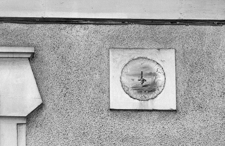 Assiette de porcelaine (motif d'oiseau) à l'angle est de la façade.