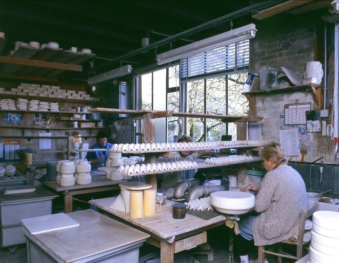 Un poste de travail de l'atelier de fabrication : opération de finissage consistant à la préparation de pièces (base de tours Eiffel) pour la cuisson au four à dégourdir.