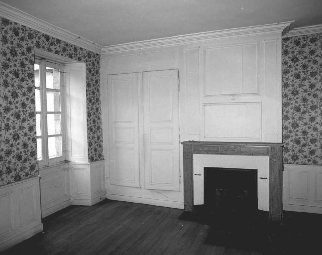 Premier étage. Vue partielle d'une pièce montrant la cheminée et ses lambris de revêtement (lambris d'appui et lambris de hauteur, formant trumeau et englobant un placard latéral).