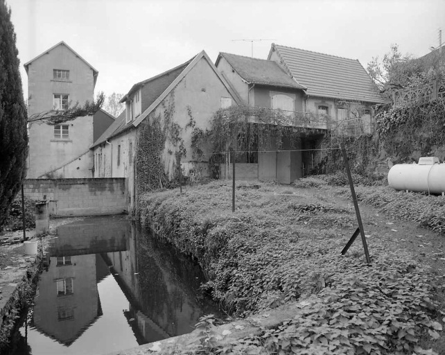 Au premier plan, le canal d'amenée en partie bouché vers 1980. Au second plan à droite, une partie de l'ancien bâtiment d'eau et le logis reconstruit au milieu du 19e siècle. A l'arrière-plan, à gauche, la minoterie.